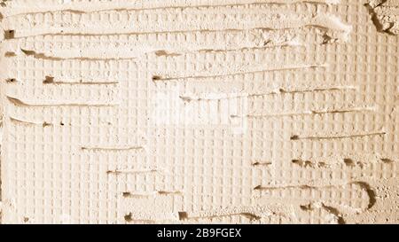 Colle pour une tuile avec un modèle d'engrenage. Installation de tuiles. La surface du mur est recouverte de pâte adhésive avant de poser des tuiles ou des s décoratifs Banque D'Images