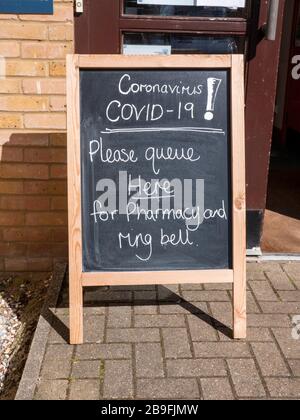 Willingham Cambridgeshire, Royaume-Uni. 24 mars 2020. Signes à la pharmacie pour protéger le personnel et les patients contre la contamination croisée du coronavirus qui n'ont pas d'autre choix que d'assister en personne. C'est le matin après que les gens du Royaume-Uni ont été informés de rester chez eux pour limiter la propagation du virus Covid 19. Crédit: Julian Eales/Alay Live News Banque D'Images