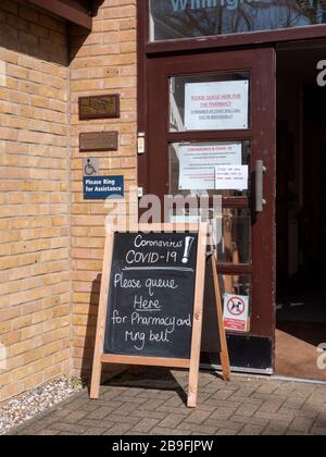 Willingham Cambridgeshire, Royaume-Uni. 24 mars 2020. Signes à la pharmacie pour protéger le personnel et les patients contre la contamination croisée du coronavirus qui n'ont pas d'autre choix que d'assister en personne. C'est le matin après que les gens du Royaume-Uni ont été informés de rester chez eux pour limiter la propagation du virus Covid 19. Crédit: Julian Eales/Alay Live News Banque D'Images