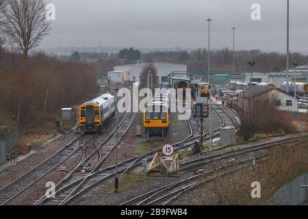 Retrait des trains de pacer de classe 142 dans une voie d'évitement au dépôt d'entretien de Newton Heath, tandis qu'une classe 158 passe sur la ligne principale. Banque D'Images