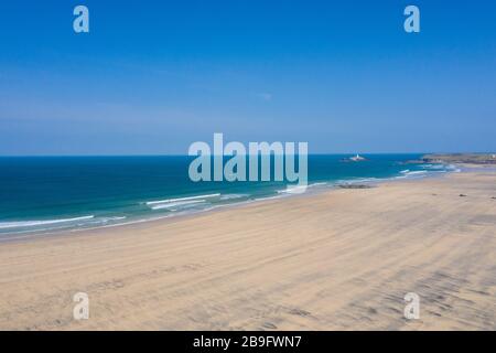 Photo aérienne d'une plage de Gwithian vide avec vagues briser et phare de rêve en arrière-plan sur une journée de ciel bleu Banque D'Images