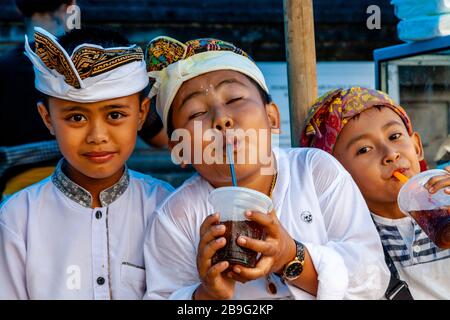 Un groupe d'enfants hindous balinais buvant des boissons gazeuses lors D'UN festival religieux local, Ubud, Bali, Indonésie. Banque D'Images