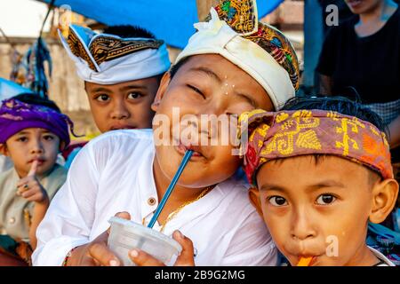 Un groupe d'enfants hindous balinais buvant des boissons gazeuses lors D'UN festival religieux local, Ubud, Bali, Indonésie. Banque D'Images