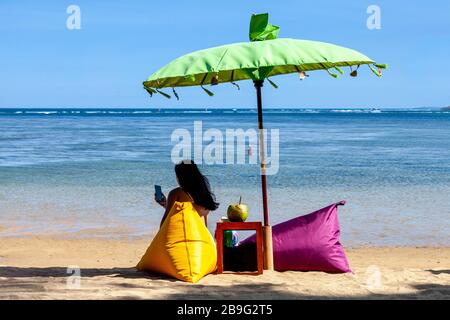 Un touriste se détend sur la plage de Sanur, Bali, Indonésie. Banque D'Images