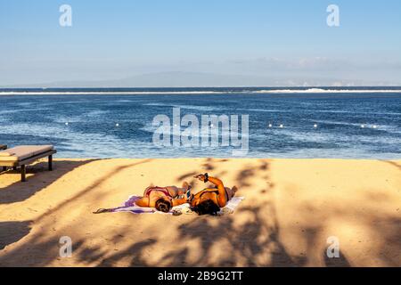 Les visiteurs peuvent bronzer sur la plage, la plage de Sanur, Bali, Indonésie. Banque D'Images