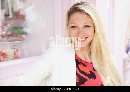Portrait souriant jeune blonde femme à l'extérieur de la boulangerie Banque D'Images