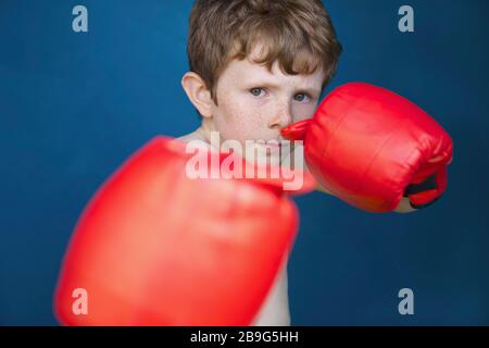 Portez un garçon résistant avec des gants de boxe pour lutter contre la position Banque D'Images