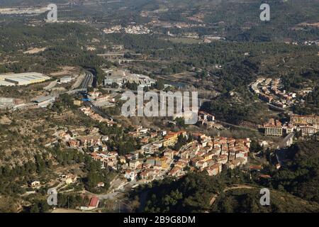 Vue aérienne de la ville de Monistrol de Montserrat illustrée de la Cremallera de Montserrat, le chemin de fer en rack reliant la ville et le monastère de Montserrat (Monasterio de Montserrat) dans le massif de montagne près de Barcelone, Catalogne, Espagne. Le dépassement du chemin de fer est vu dans le centre et la gare est vue à gauche. Banque D'Images