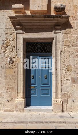 Porte en bois bleu vintage dans un mur en pierre jaune. Mdina, vieille ville fortifiée dans la région du Nord de Malte Banque D'Images