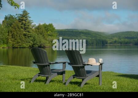 Deux chaises adirondack sur l'herbe à côté face au lac Bomoseen & montagnes un matin de printemps à Castleton, VT Banque D'Images