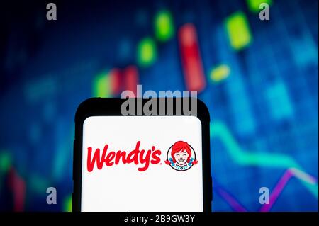 Pologne. 23 mars 2020. Dans cette illustration photo, un logo Wendys apparaît sur un smartphone.un graphique de la bourse est affiché en arrière-plan. Crédit: Mateusz Slodkowski/SOPA Images/ZUMA Wire/Alay Live News Banque D'Images