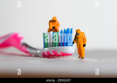 Une image conceptuelle pour le Coronavirus montrant des tests pour les bactéries sur une brosse à dents utilisant des personnes miniatures dans des costumes hazmat. Banque D'Images