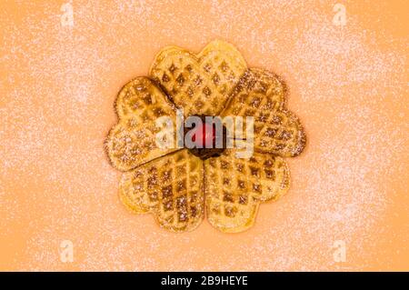 Gaufres maison avec sucre en poudre, une boule de glace à la vanille et une cerise sur fond rose, image isolée de la nourriture. Banque D'Images