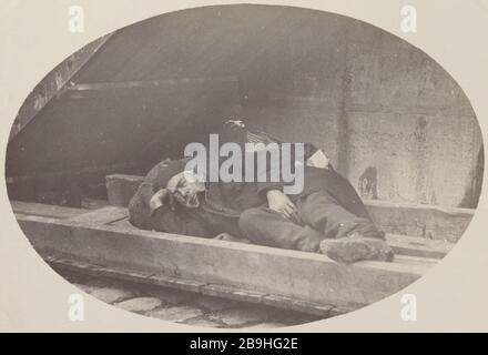 TRAMP ENDORMI SOUS LES ESCALIERS, QUAI BOURBON Clochard endormi sous un escalier, quai de Bourbon. Paris (IVème arr.), vers 1900. Photo de Louis Vert (1865-1924). Paris, musée Carnavalet. Banque D'Images