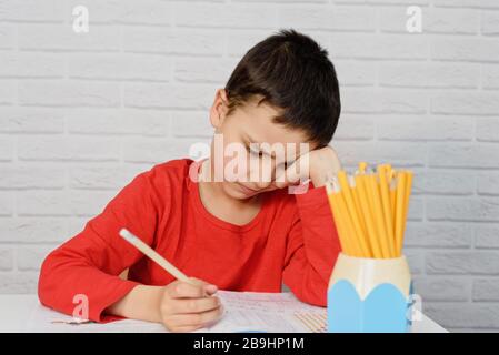 Énervé ennuyant l'école qui fait des devoirs. Concept d'éducation, d'école, de difficultés d'apprentissage. Enfant fatigué de faire des devoirs étudier avec le stylo sur les livres ouverts Banque D'Images