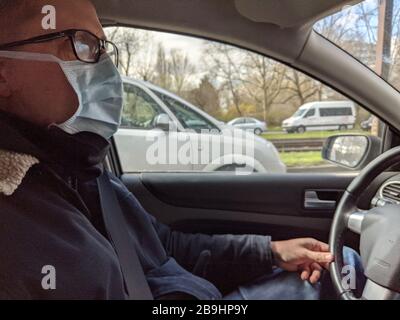 Homme avec masque de visage en voiture à travers la ville Banque D'Images