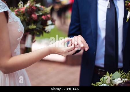 Mariée mettant l'anneau de mariage doré sur le doigt de groom. Cérémonie de mariage Banque D'Images