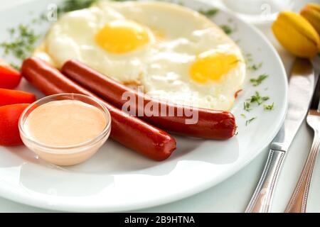 Délicieux petit déjeuner saucisses et œufs frits avec tomates Banque D'Images