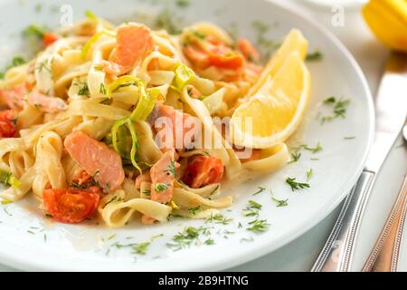 Délicieuses pâtes tagliatelles au saumon, aux tomates, à l'oignon et au citron. Spaghetti de fruits de mer italiens avec saumon et sauce Banque D'Images