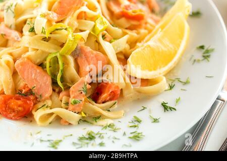 Tagliatelle pâtes de fruits de mer avec saumon, tomates, oignons et citron. Recette de pâtes italiennes Banque D'Images