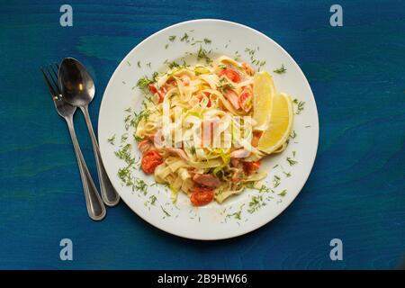 Des spaghettis de fruits de mer italiens savoureux avec du saumon. Tagliatelle pâtes avec poisson, tomate, oignon et sauce sur fond bleu en bois Banque D'Images