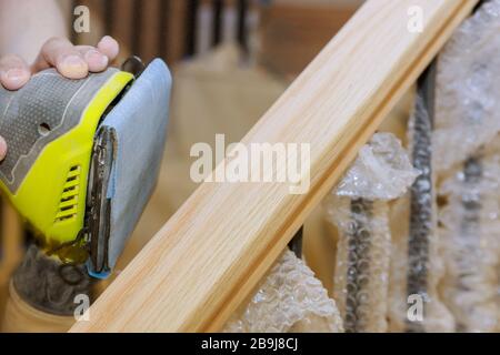 Ponçage à la rampe en bois avec du papier de verre pour le travail de la meuleuse d'escaliers dans le bois de bois Banque D'Images