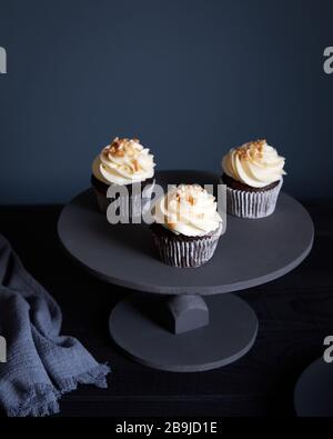Cupcakes au chocolat avec crème au beurre blanc et arachides sur fond sombre avec espace libre pour votre texte Banque D'Images