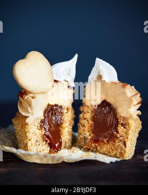 Coupe de cupcake de Carrot au caramel, noix et épices décorées de biscuit en forme de coeur, meringue et caramel salé sur fond sombre gros plan Banque D'Images