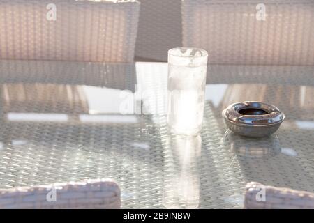 Verre froid glacé d'eau goutte d'eau sur la table en verre avec cendrier Banque D'Images