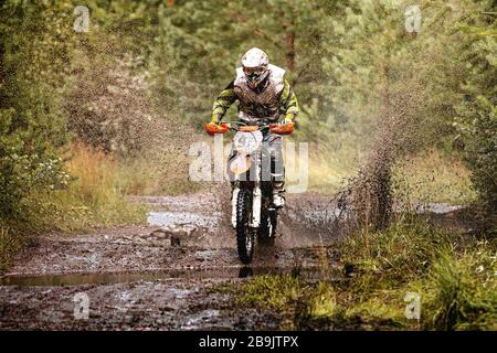 motocross enduro athlète de course à cheval sur un sentier boueux et humide dans la forêt Banque D'Images
