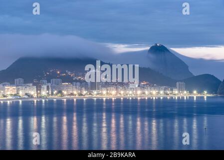 Belle vue sur la plage de Copacabana et les bâtiments à l'heure bleue avec le mont du pain de sucre à l'arrière, Rio de Janeiro, Brésil Banque D'Images