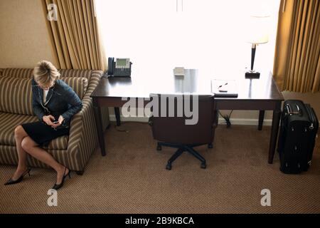 Une femme d'aide d'un téléphone mobile dans sa chambre d'hôtel. Banque D'Images