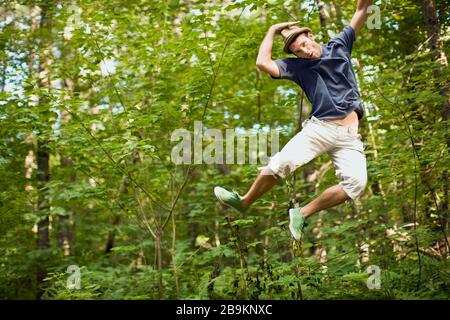 Jeune homme sautant dans le milieu de l'air dans une forêt Banque D'Images