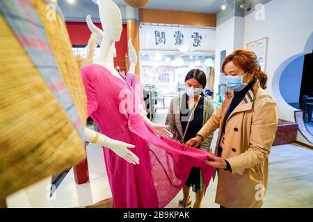 (200324) -- CHONGQING, le 24 mars 2020 (Xinhua) -- les clients choisissent des produits de la maison de gazon de Rongchang, également appelée Rongchang Xiabu, dans un magasin du district de Rongchang à Chongqing, dans le sud-ouest de la Chine, le 23 mars 2020. Le linge de gazon de Rongchang est un artisanat chinois traditionnel avec une riche histoire. C'est une sorte de tissu fait de ramie purement à la main, et célèbre pour sa texture douce, fine, plate et de qualité fine. Parce que ce tissu garde habituellement le corps frais dans l'été chaud, il est également appelé Xiabu (littéralement, le tissu d'été). Avec des mesures complètes de prévention des épidémies, Xiabu Making industrie Banque D'Images