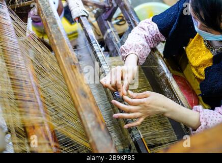 (200324) -- CHONGQING, le 24 mars 2020 (Xinhua) -- une femme fait du linge de maison de gazon de Rongchang, également appelé Rongchang Xiabu, lors d'un atelier dans le district de Rongchang à Chongqing, dans le sud-ouest de la Chine, le 23 mars 2020. Le linge de gazon de Rongchang est un artisanat chinois traditionnel avec une riche histoire. C'est une sorte de tissu fait de ramie purement à la main, et célèbre pour sa texture douce, fine, plate et de qualité fine. Parce que ce tissu garde habituellement le corps frais dans l'été chaud, il est également appelé Xiabu (littéralement, le tissu d'été). Grâce à des mesures de prévention des épidémies globales, les industries de fabrication de Xiabu y ont Banque D'Images