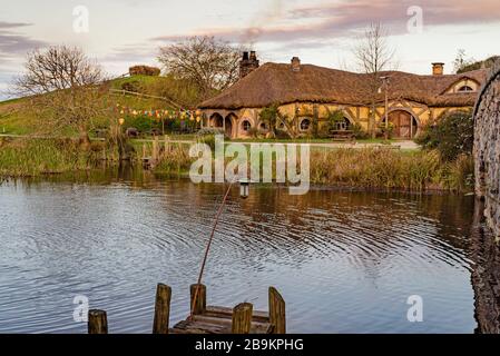 Vue sur le lac jusqu'au Green Dragon Inn au Hobbiton Movie Set, Nouvelle-Zélande Banque D'Images