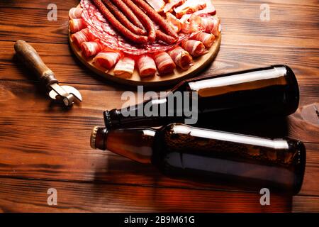 En-cas de bière sous forme de produits à base de viande et de bière en bouteille. Apéritif sous forme de bacon à trancher, salami, jambon, saucisses de chasse. Stock de bière photo et Banque D'Images