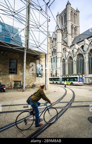 Un homme traverse la rue en vélo à côté de l'église Saint-Nicolas dans un matin nuageux. Banque D'Images