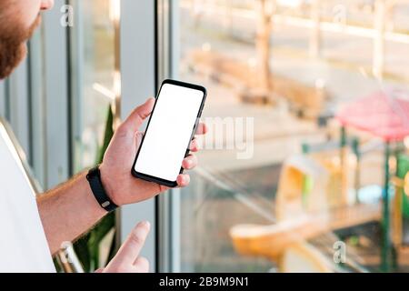 Smartphone Mockup dans un téléphone portable noir avec écran blanc vide, écran d'espace de copie pour votre texte ou votre conception ou application derrière la fenêtre au bureau Banque D'Images