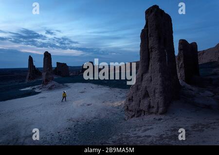 Femme avec un phare léger debout à couper le souffle ruines de la forteresse Jampik Kala situé dans le désert de Kyzylkum dans la région de Karakalpakstan en Ouzbékistan Banque D'Images