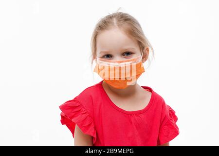 Gros plan portrait mignonne petite fille posant dans le masque de protection médicale isolé dans le studio blanc