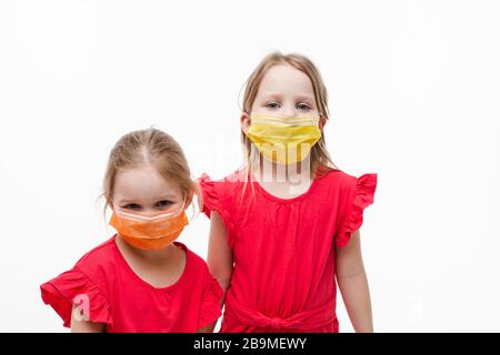 Deux mignonne petite fille posant dans un masque médical de protection isolé à fond blanc de studio