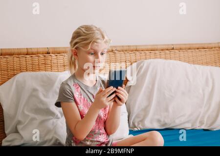 Jolie fille caucasienne adorable rester à la maison et appeler ses amis sur smartphone. Enfant enfant enfant ayant le temps de face appeler parler avec les parents pendant que sur soi Banque D'Images