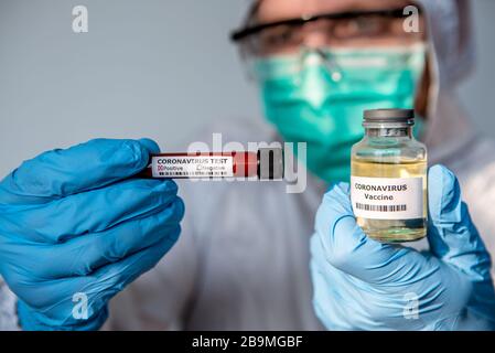 Un homme scientifique avec combinaison de protection est titulaire d'un vaccin contre le coronavirus. Homme caucasien avec tube d'essai négatif de l'échantillon de sang infecté et la vaccination Banque D'Images