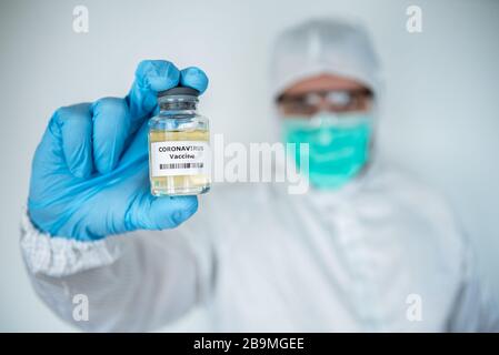 Les hommes scientifiques avec combinaison de protection détiennent un vaccin contre le coronavirus. Homme caucasien avec vaccination pour COVID-19. 2019-nCoV trouvé dans Wuhan Chine. EPI Banque D'Images