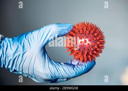 Médecin en laboratoire qui détient un modèle rouge de coronavirus. Homme scientifique sur une combinaison de protection avec une molécule de COVID19. Soins médicaux et de santé Banque D'Images