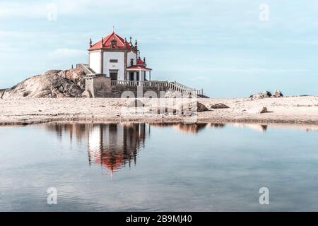 Chapelle solitaire sur la plage se reflétant dans l'eau, Costa Nova Beach, Aveiro, Portugal, novembre 2019 Banque D'Images