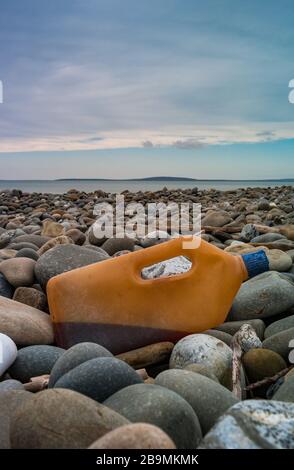 Conteneur de bouteilles en plastique avec déchets liquides lavé sur le rivage de la côte ouest de l'Irlande Banque D'Images