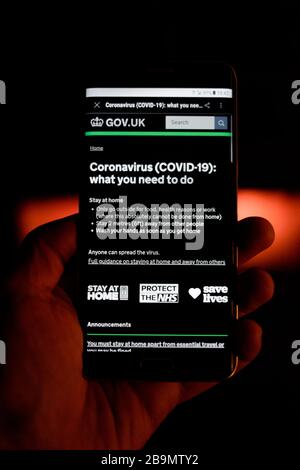 smartphone de main masculine montrant l'alerte reçue du gouvernement concernant ce que vous devez faire au sujet de la pandémie de coronavirus au royaume-uni Banque D'Images