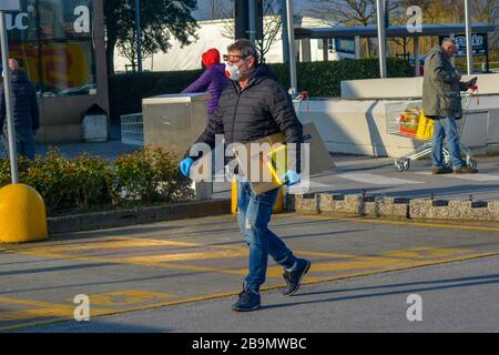 Toscana, Italie 03/21/20 - vieil homme italien portant un masque chirurgical de protection contre le coronavirus avec des sacs à provisions sous son bras. Achat de panique, anxiété et fe Banque D'Images